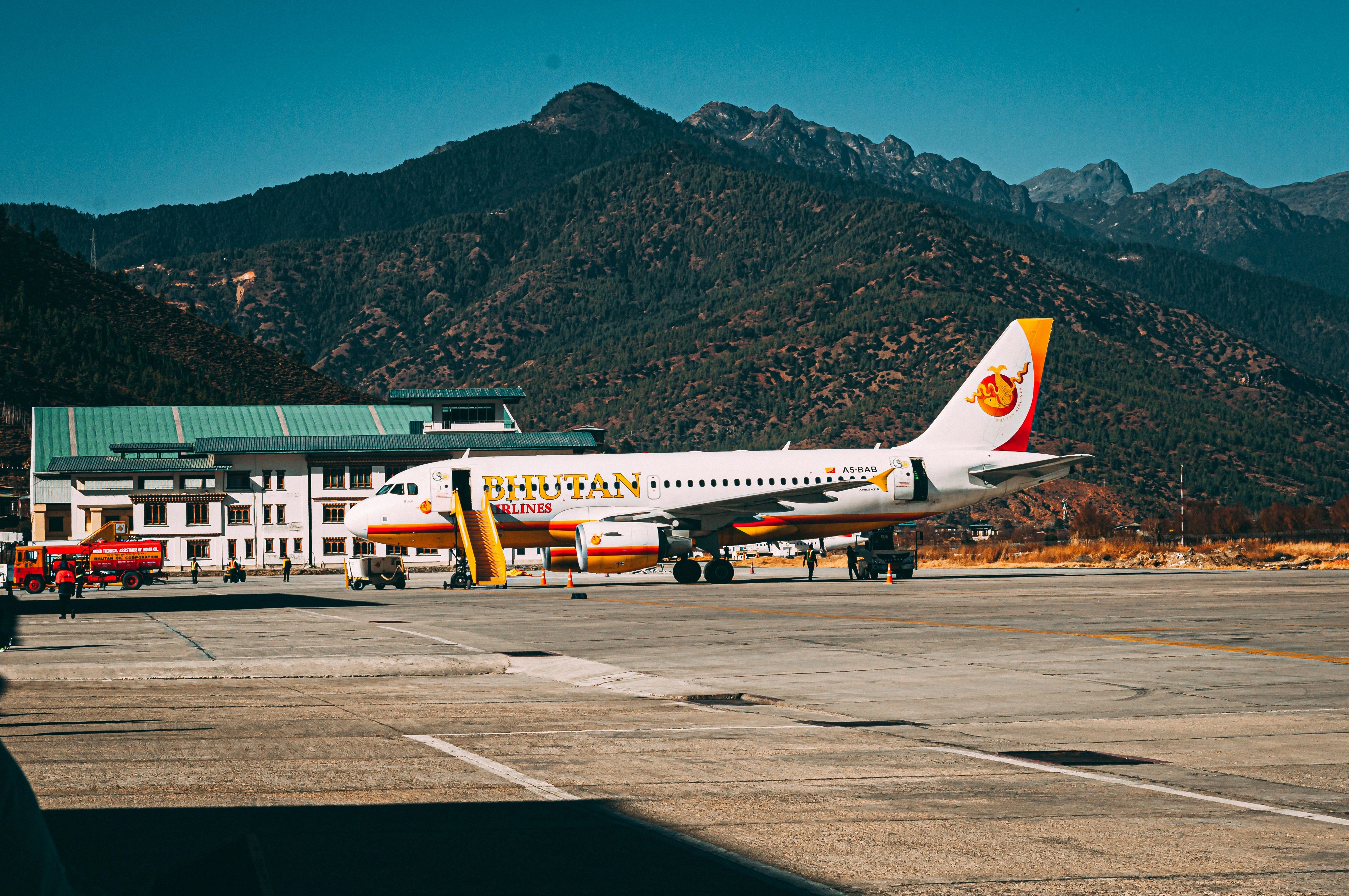 A Bhutan Airlines aircraft parked at Paro International Airport with scenic mountain backdrop