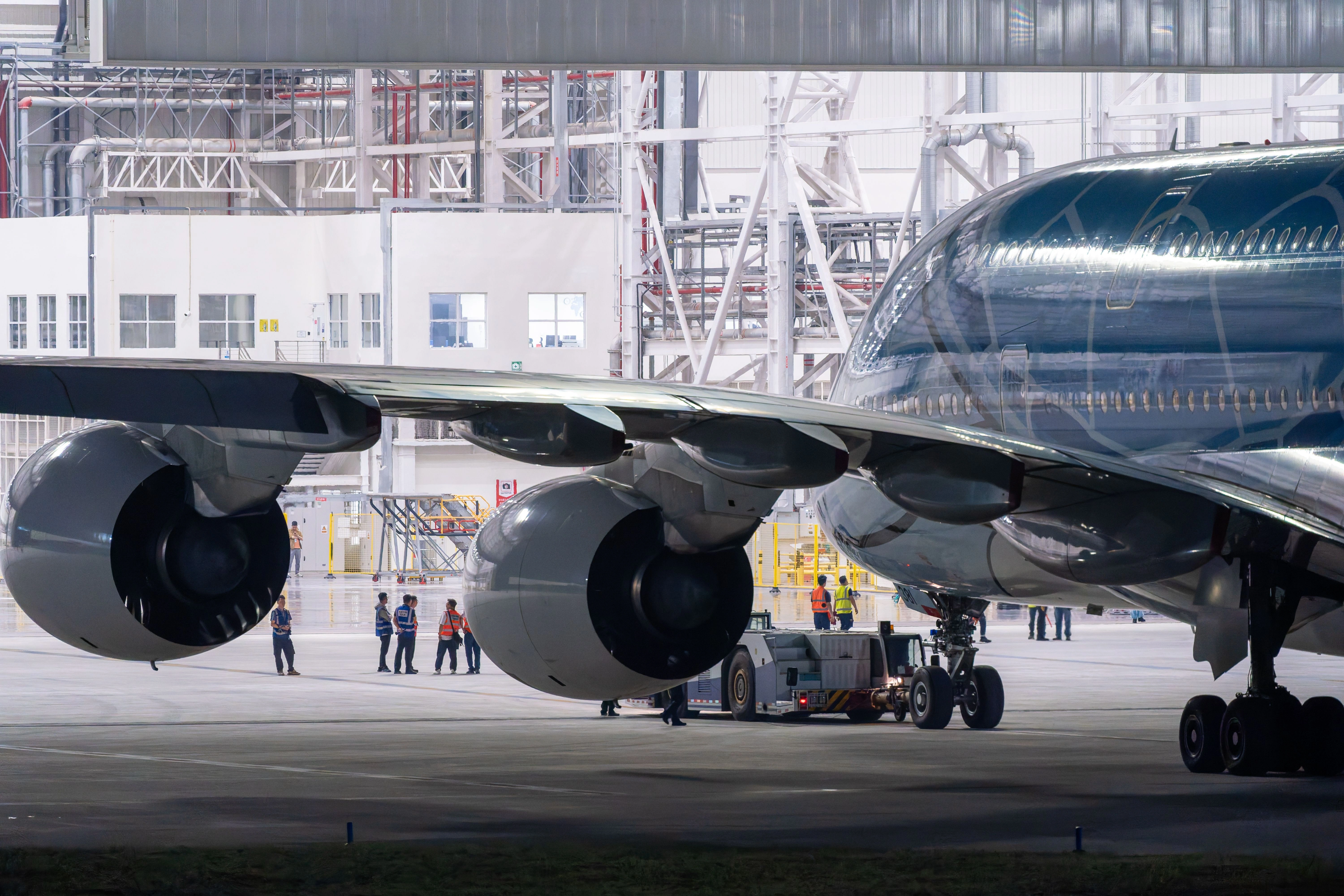 Aviation maintenance technician working underneath an aircraft in a hangar bay