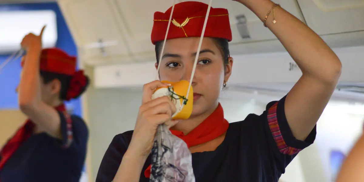 Flight-attendant-demonstrating-how-to-use-an-oxygen-mask-during-pre-flight-safety-instructions