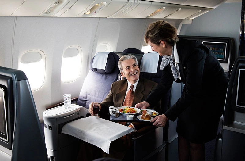 flight attendant serving passengers with meals on business class