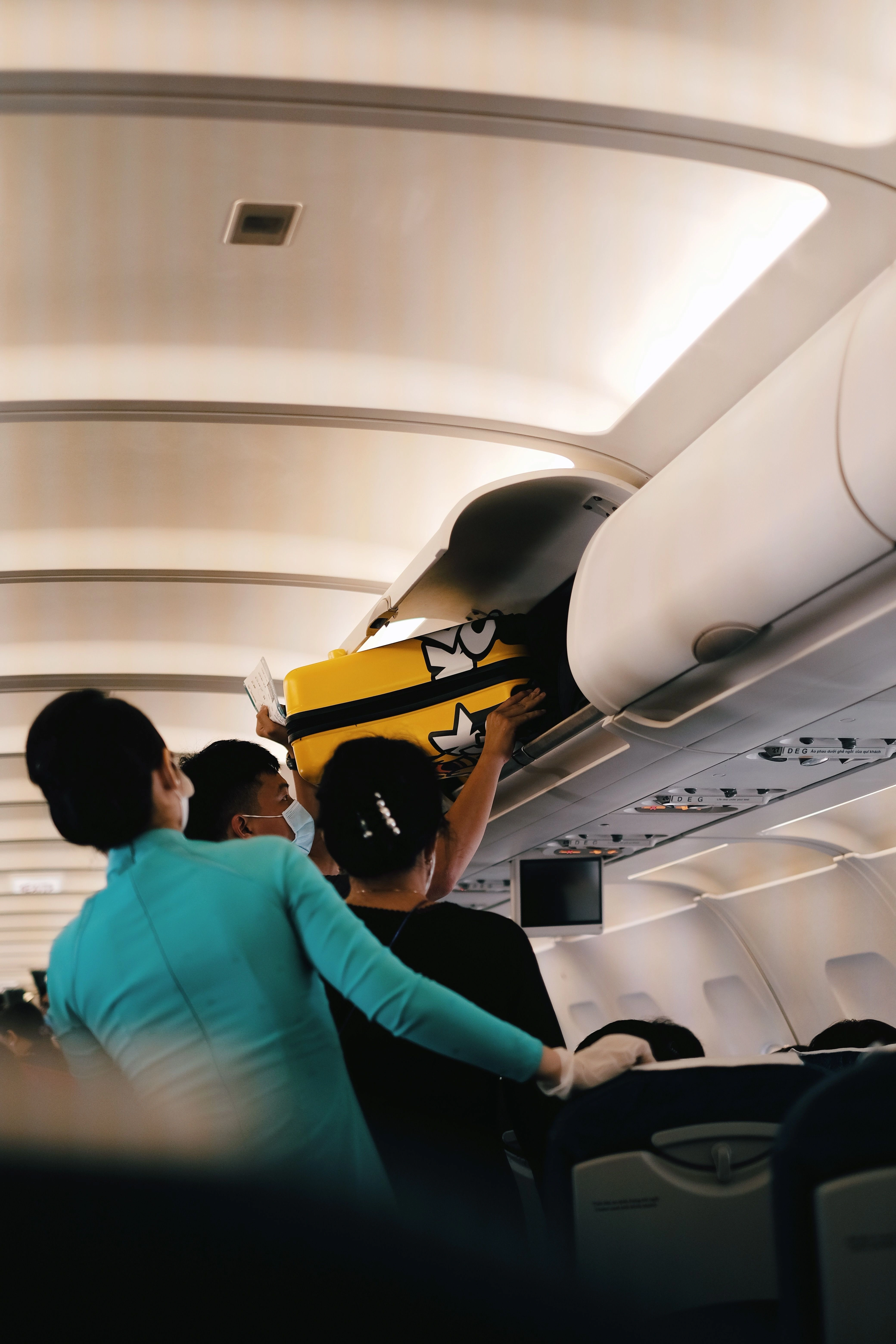 flight attendants helping passengers with carryons on flight