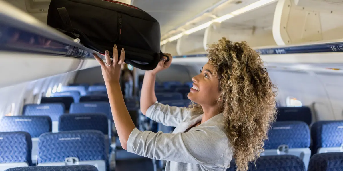 In american airlines girl putting baggages on overhead bin size