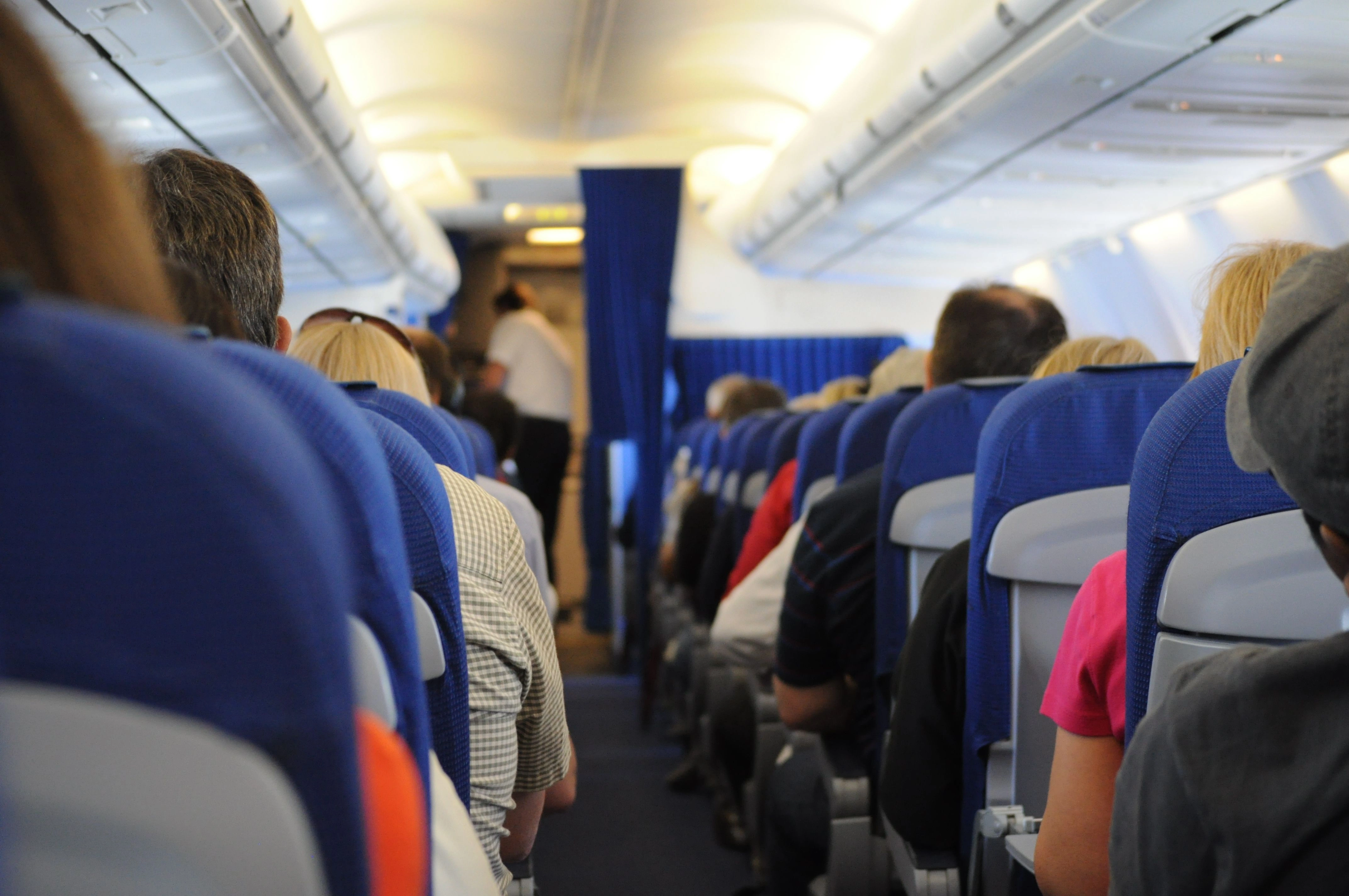 Interior view of an airplane cabin aisle with passengers seated