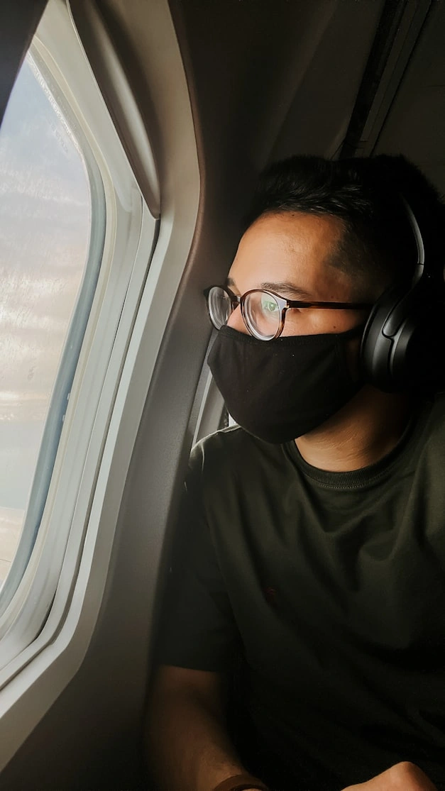 passenger wearing black headphone looking out of united airlines window