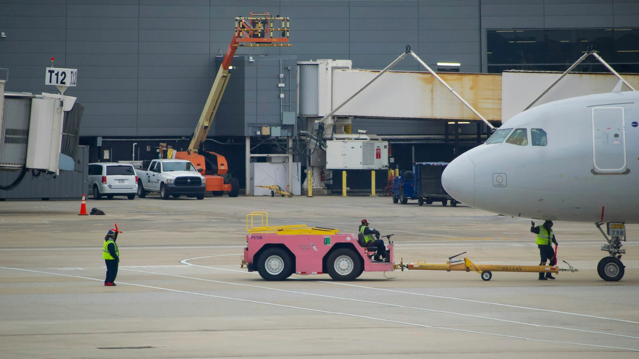 pushback crew detaching tow bar from aircraft at Atlanta airport with pink pushback tug