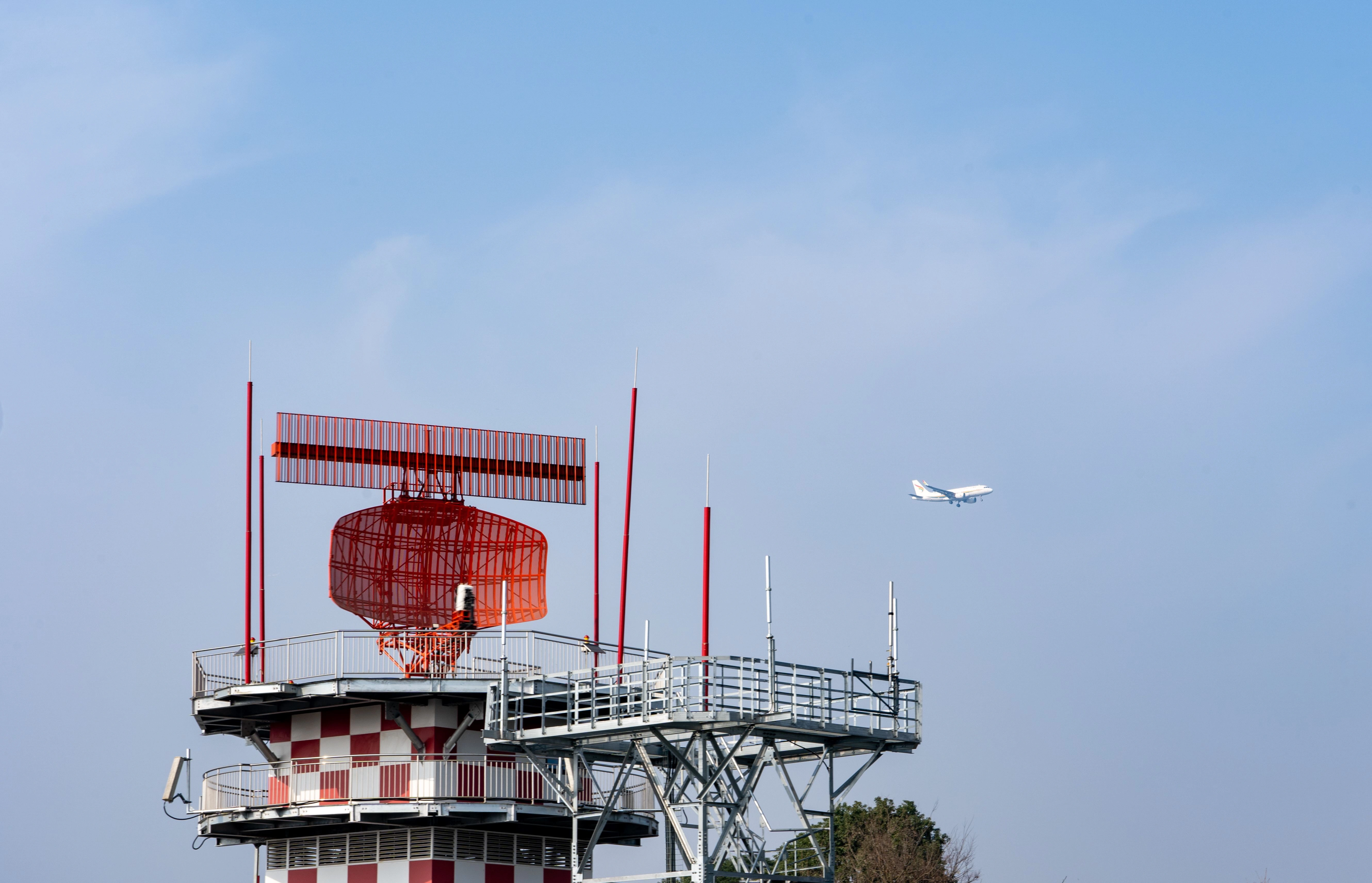 radar tower and airplane in a clear blue sky showcasing aviation technology