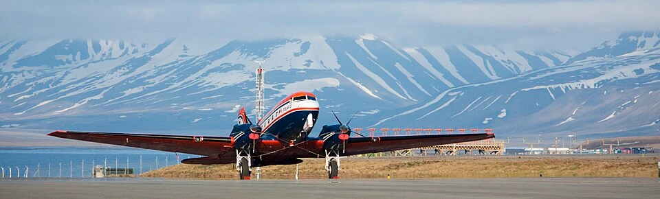 Small aircraft parked on the runway at Svalbard Airport near Longyearbyen, with Arctic mountains in the background
