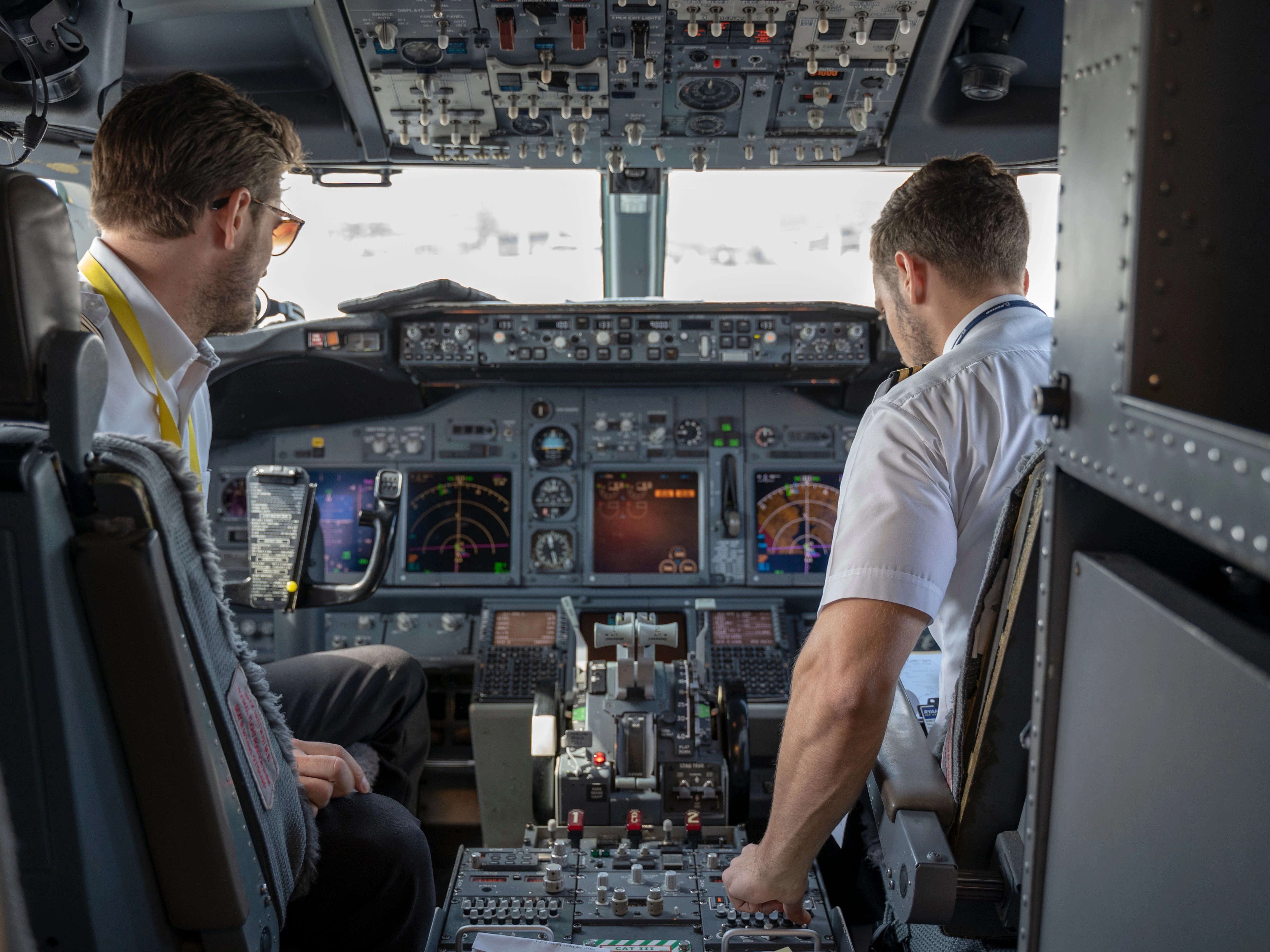 Two pilots navigating aircraft cockpit focused on advanced avionics and flight systems