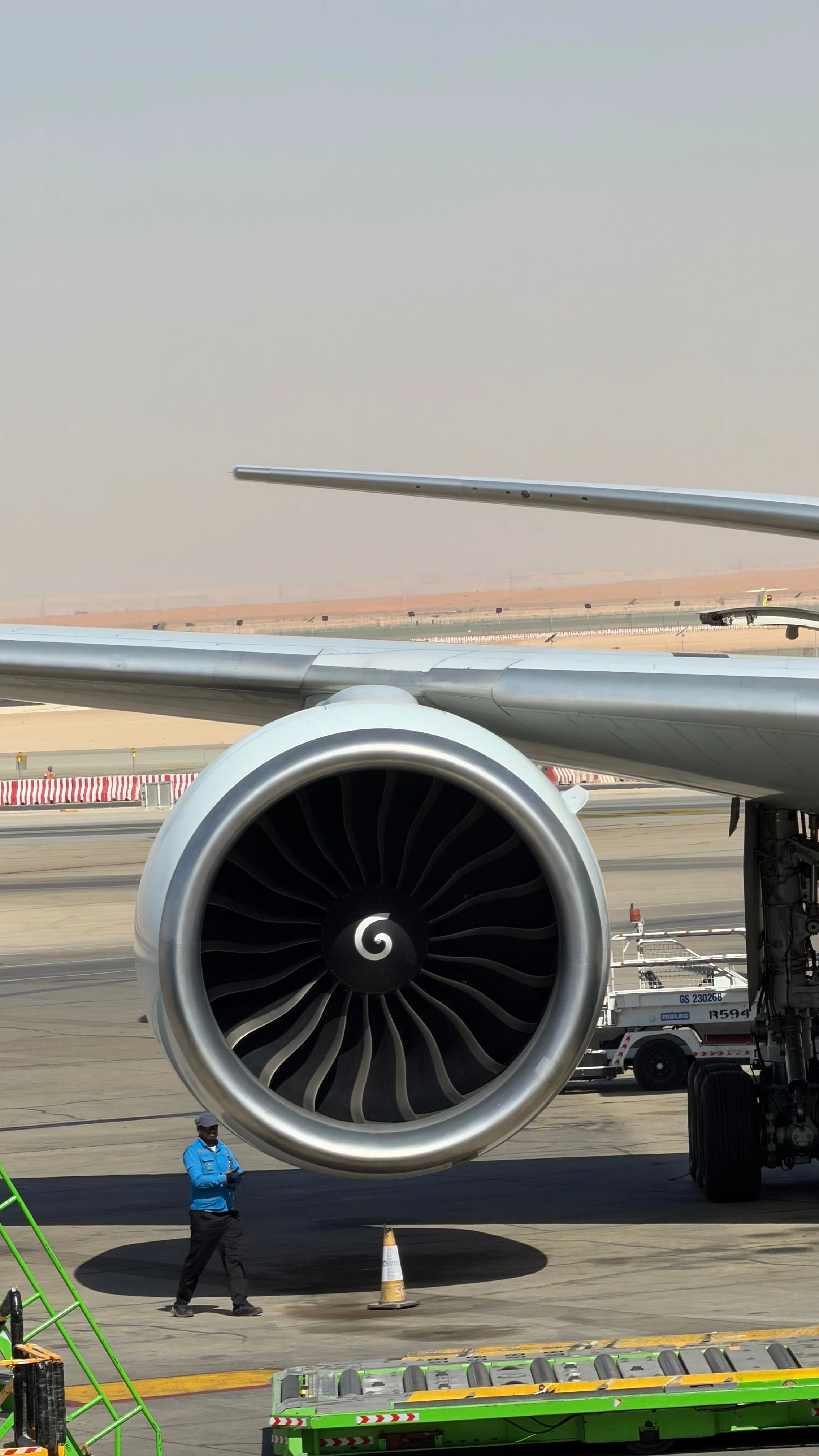 view of a commercial airplane jet engine with a technician nearby on the runway tarmac